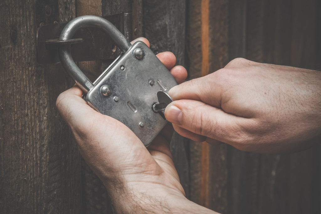 Hands with old door lock and a key. Wooden doors. Vintage style.