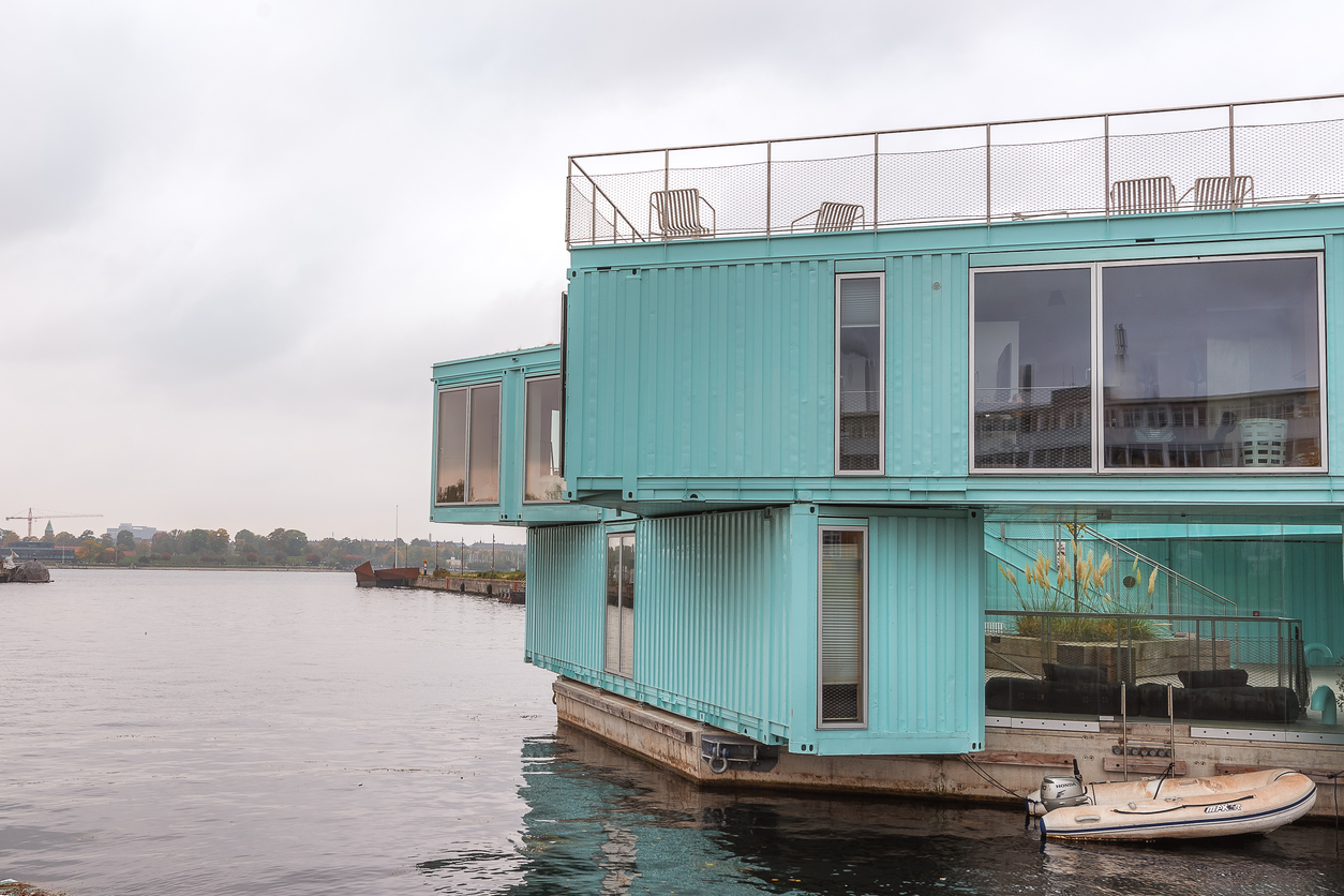 Teal blue shipping containers converted to holiday home on the edge of a lake
