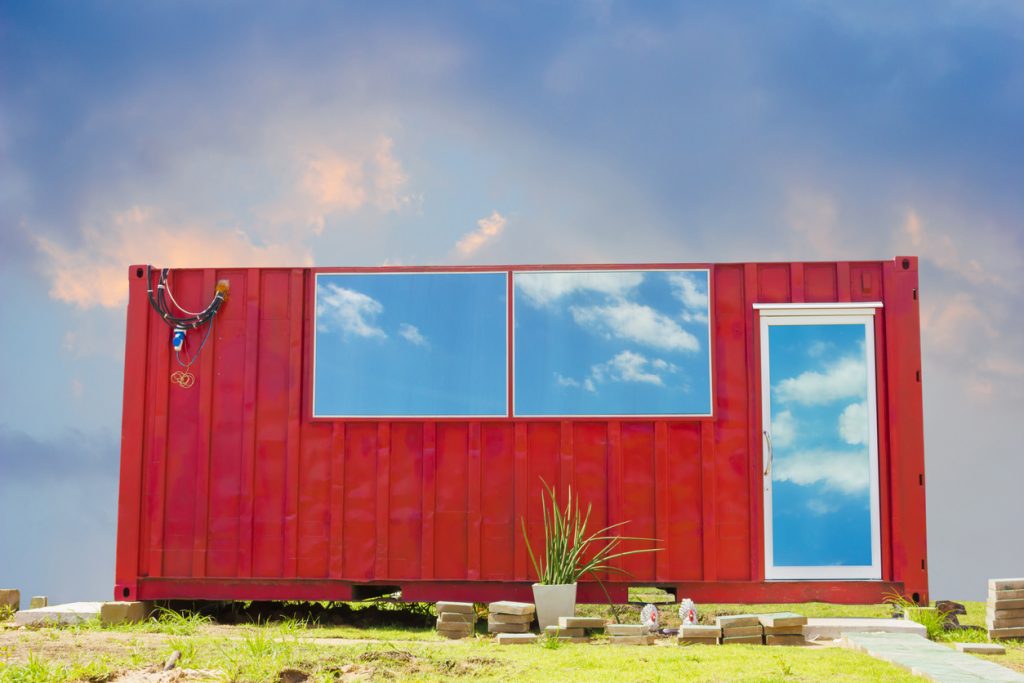 Bright red shipping container converted to holiday home with windows and a door